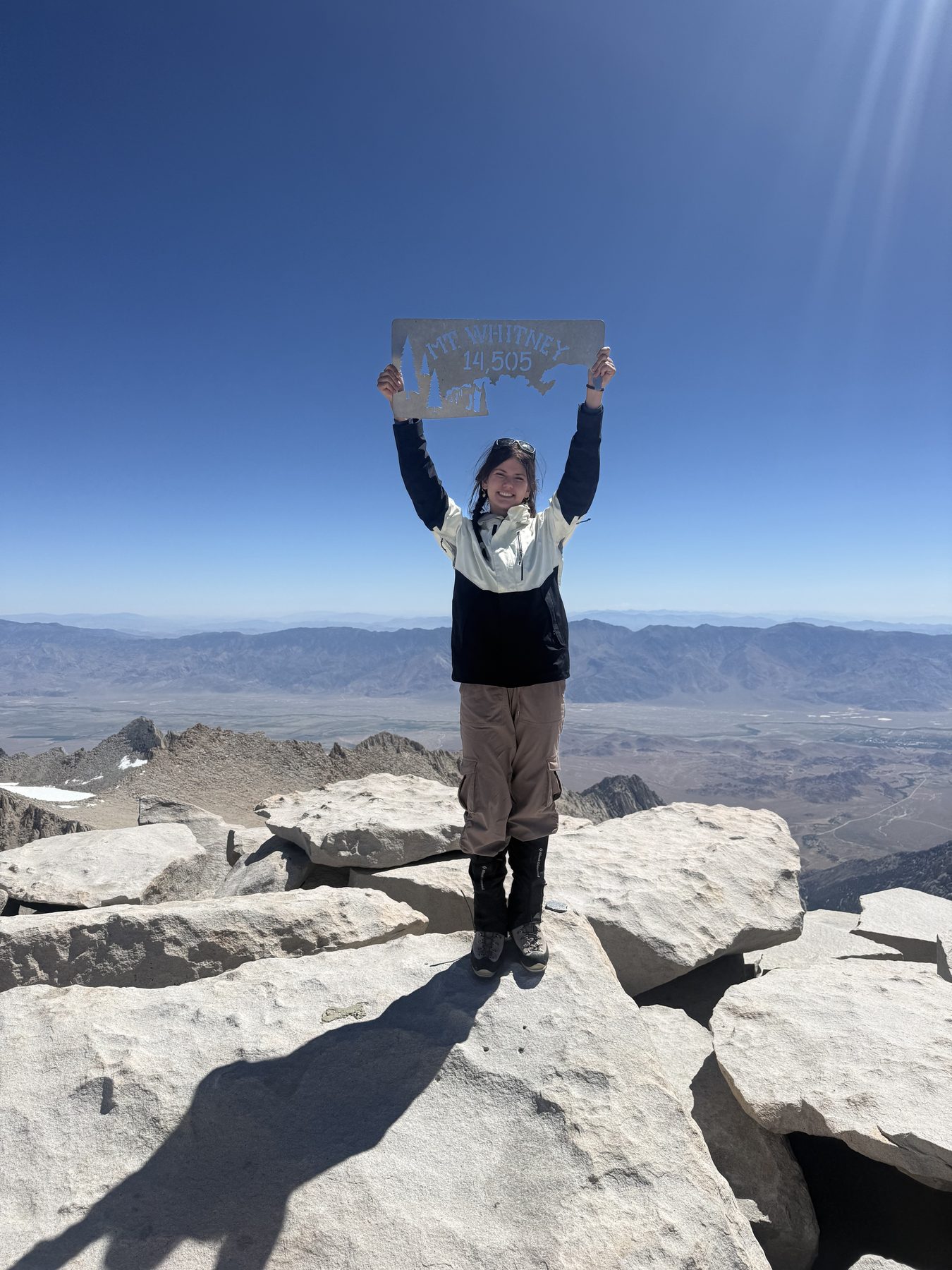 Stella at the summit of Mount Whitney holding the 14,505-foot elevation sign