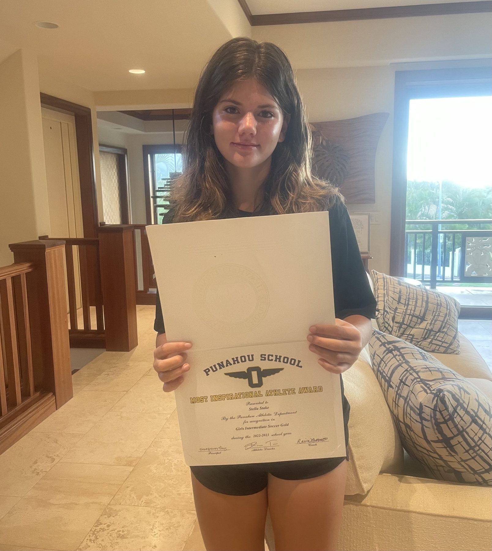 Stella holding Punahou Most Inspirational Athlete Award for girls soccer