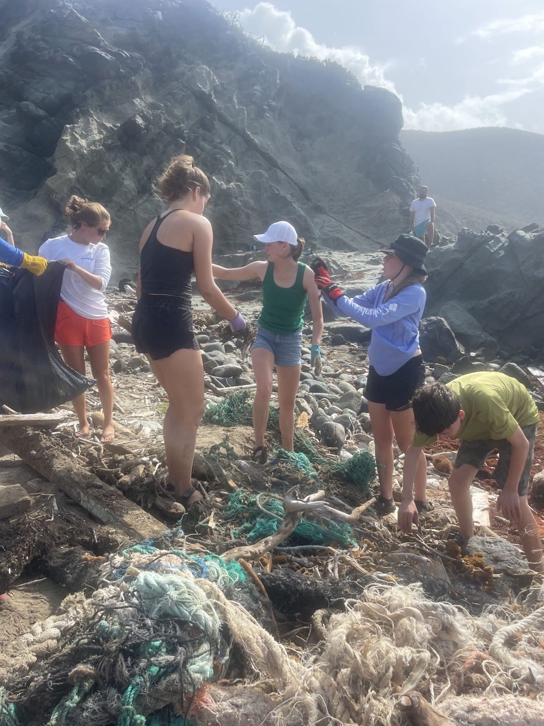 Students removing abandoned fishing nets on a rocky Virgin Islands shoreline