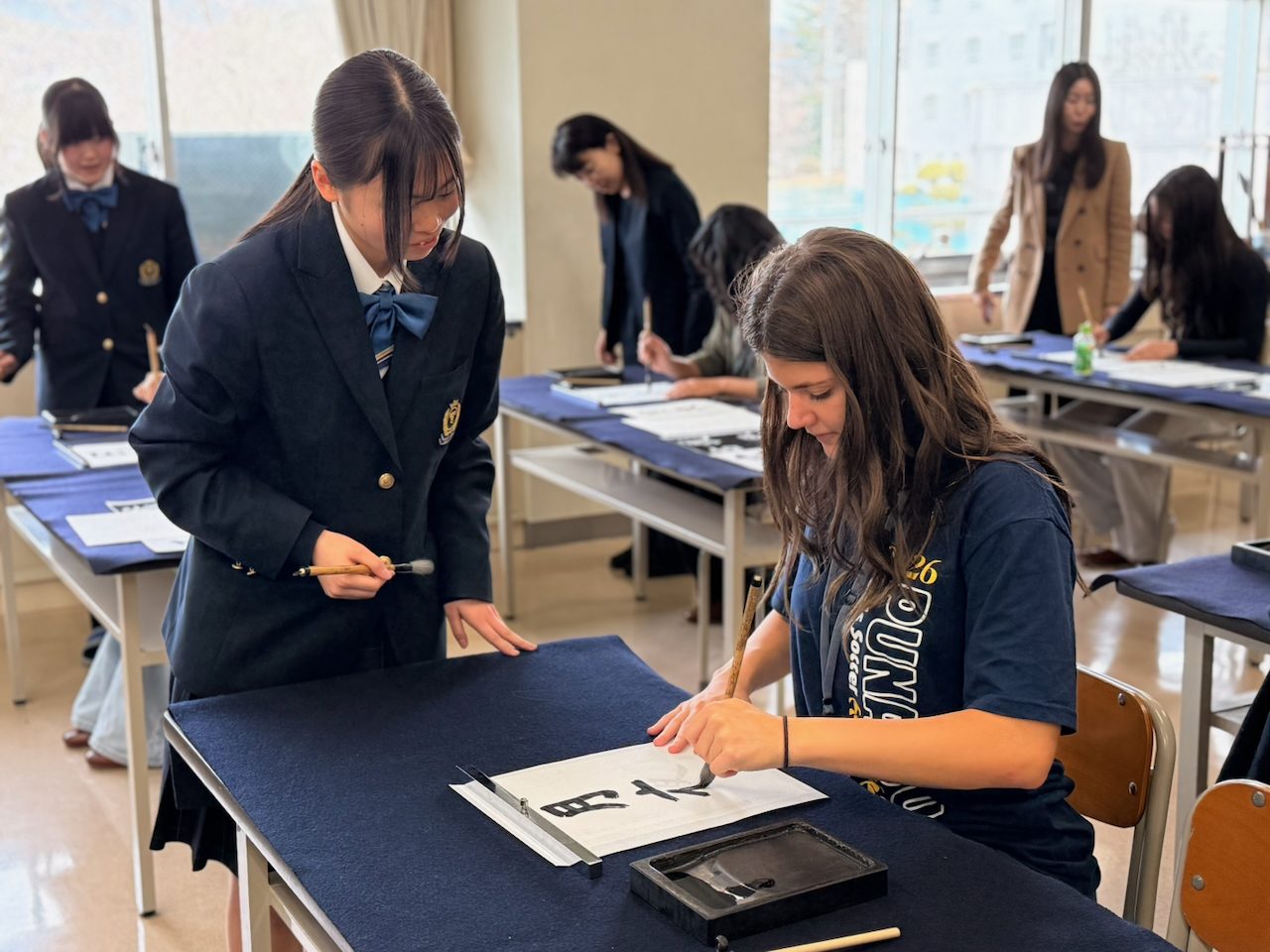 Stella practicing calligraphy with a Chino high school student