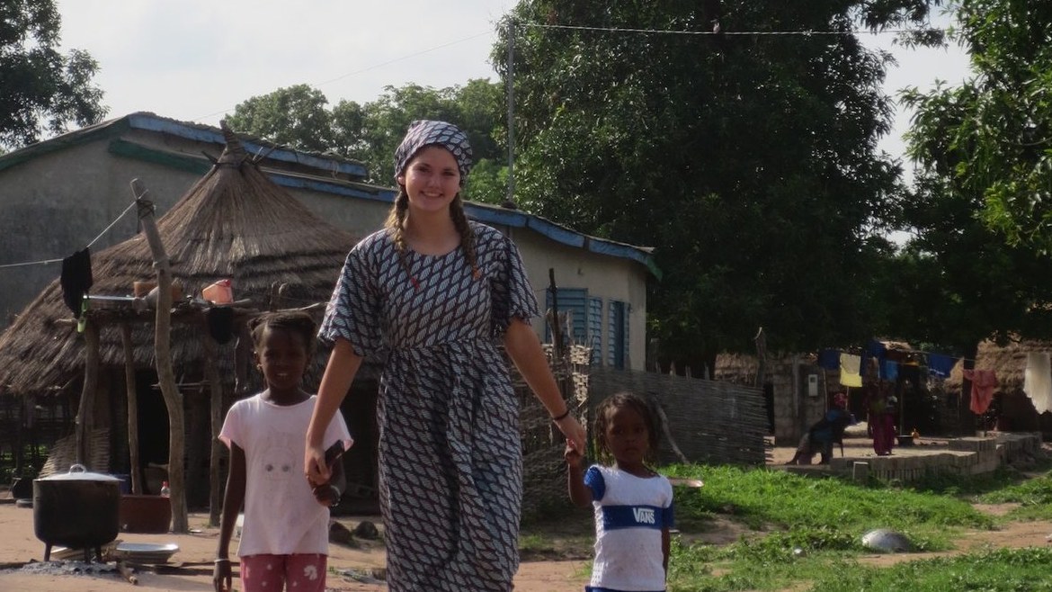 Stella walking hand in hand with children in a Senegalese village