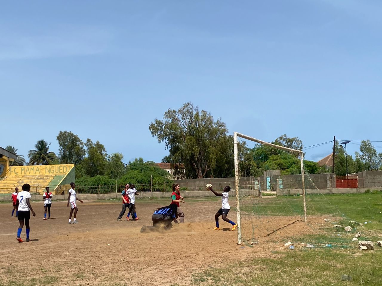 Girls playing soccer on a dirt field in Senegal