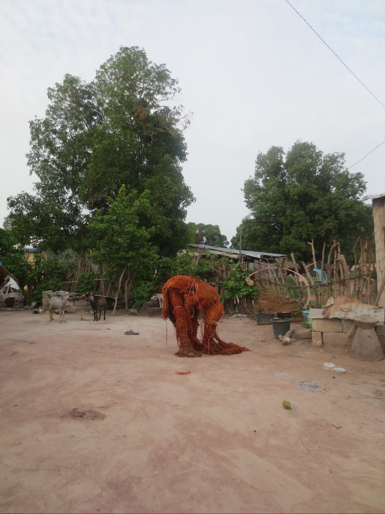 A Kankurang masquerade figure in a village compound